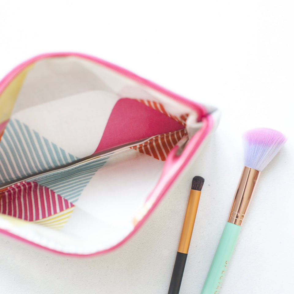 Trousse de maquillage ouverte à côté de pinceaux sur fond blanc Image