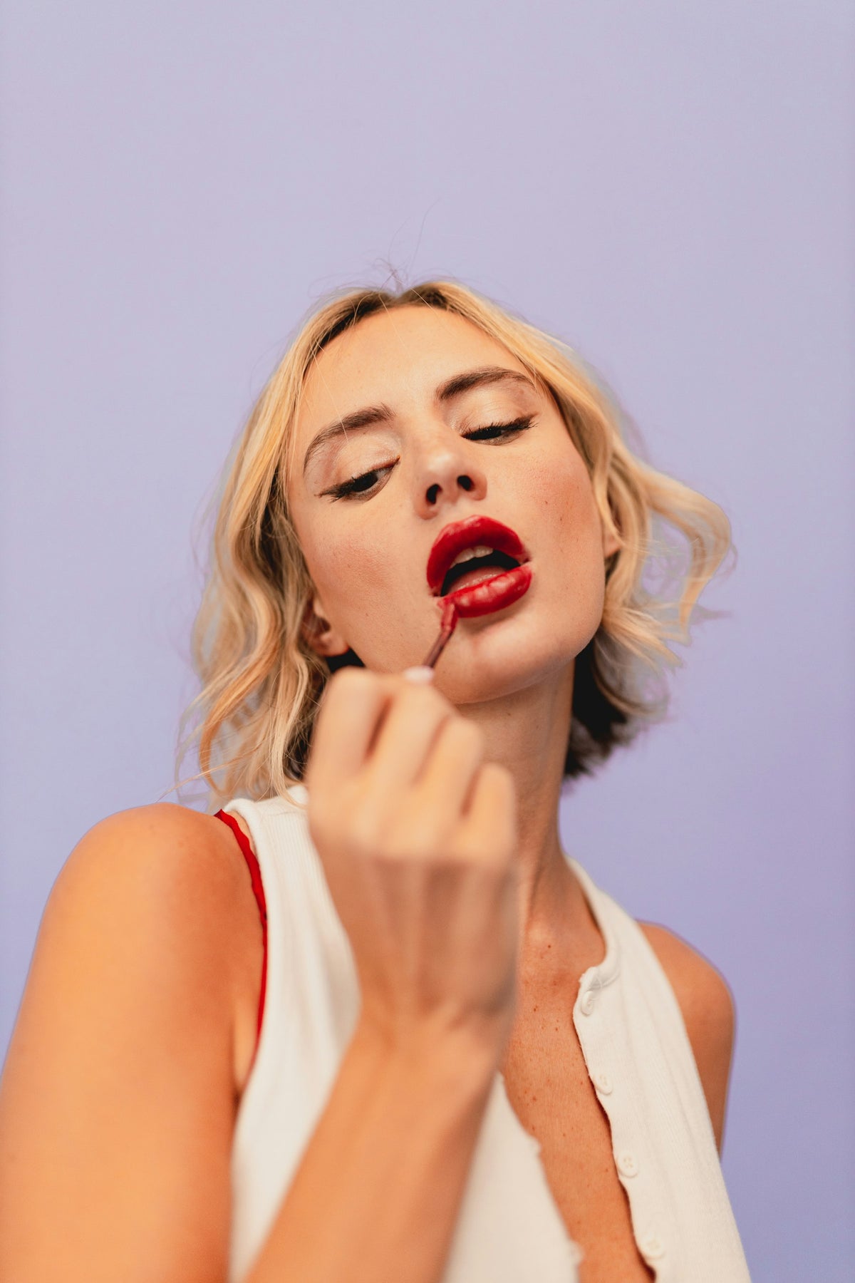 Femme blonde appliquant un rouge à lèvres rouge Image
