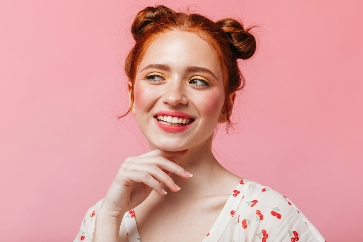 Jeune femme rousse souriante sur fond rose Image